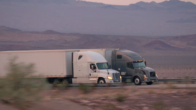 CLOSE UP: Freight semi truck driving and transporting cargo container on busy highway, delivering goods. Trucks speeding and overtaking